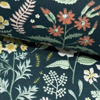 Fabric patterned with coral red and yellow meadow flowers and green leaves on dark green background.