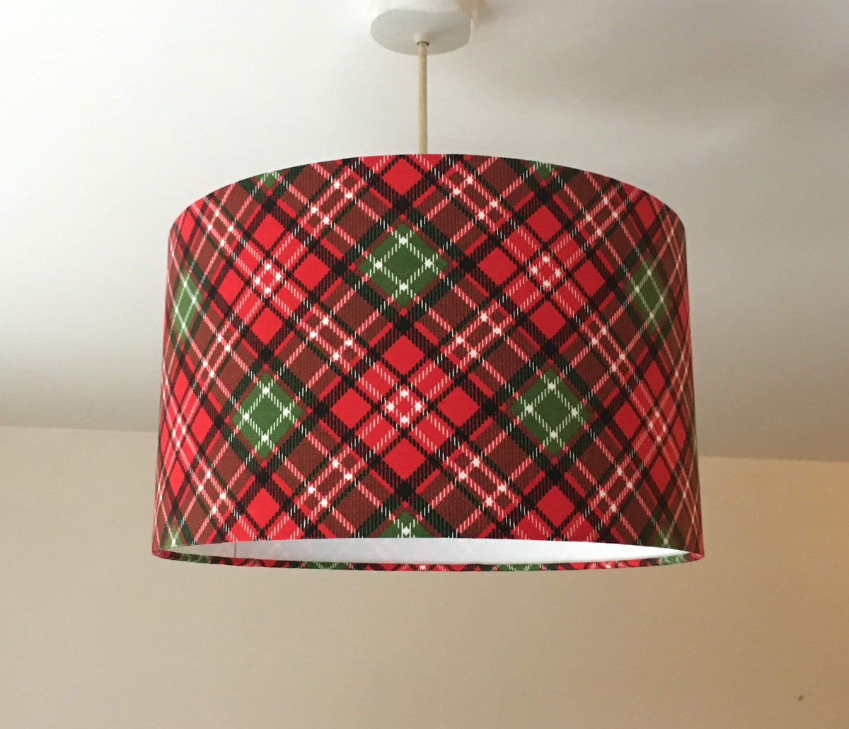 Red and green plaid lampshade on a white ceiling.