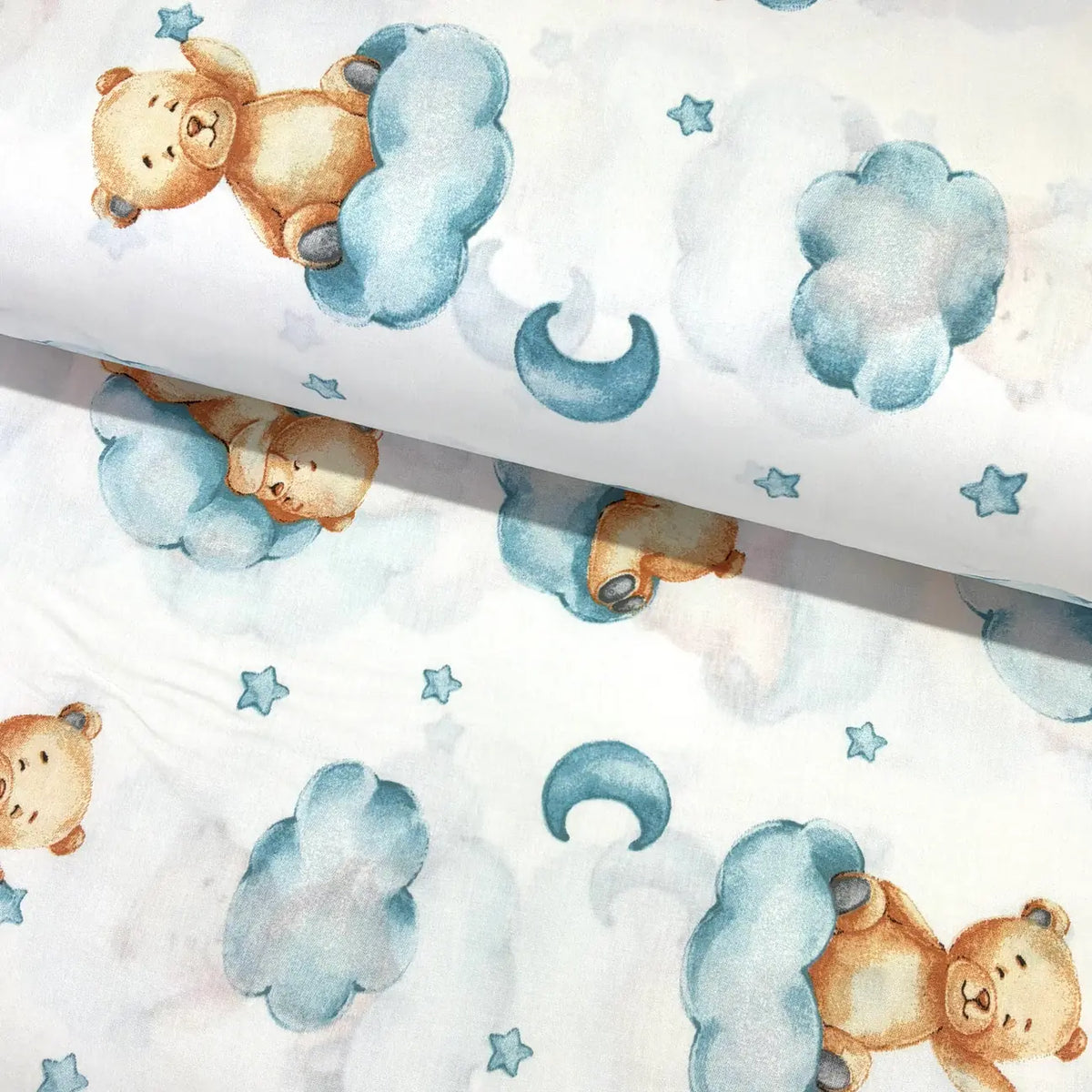 Sleeping teddy bear cotton fabric featuring blue clouds with moons and stars on a white background.