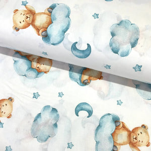 Sleeping teddy bear cotton fabric featuring blue clouds with moons and stars on a white background.