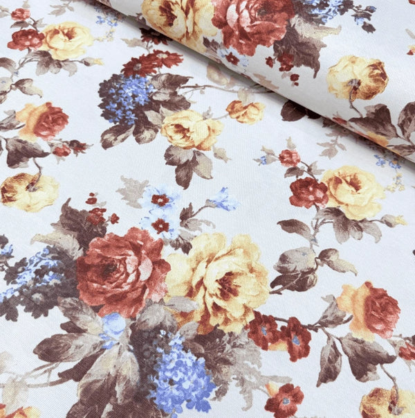 Floral upholstery fabric with a pattern of brick red, yellow and blue flowers and brown leaves on a white background.