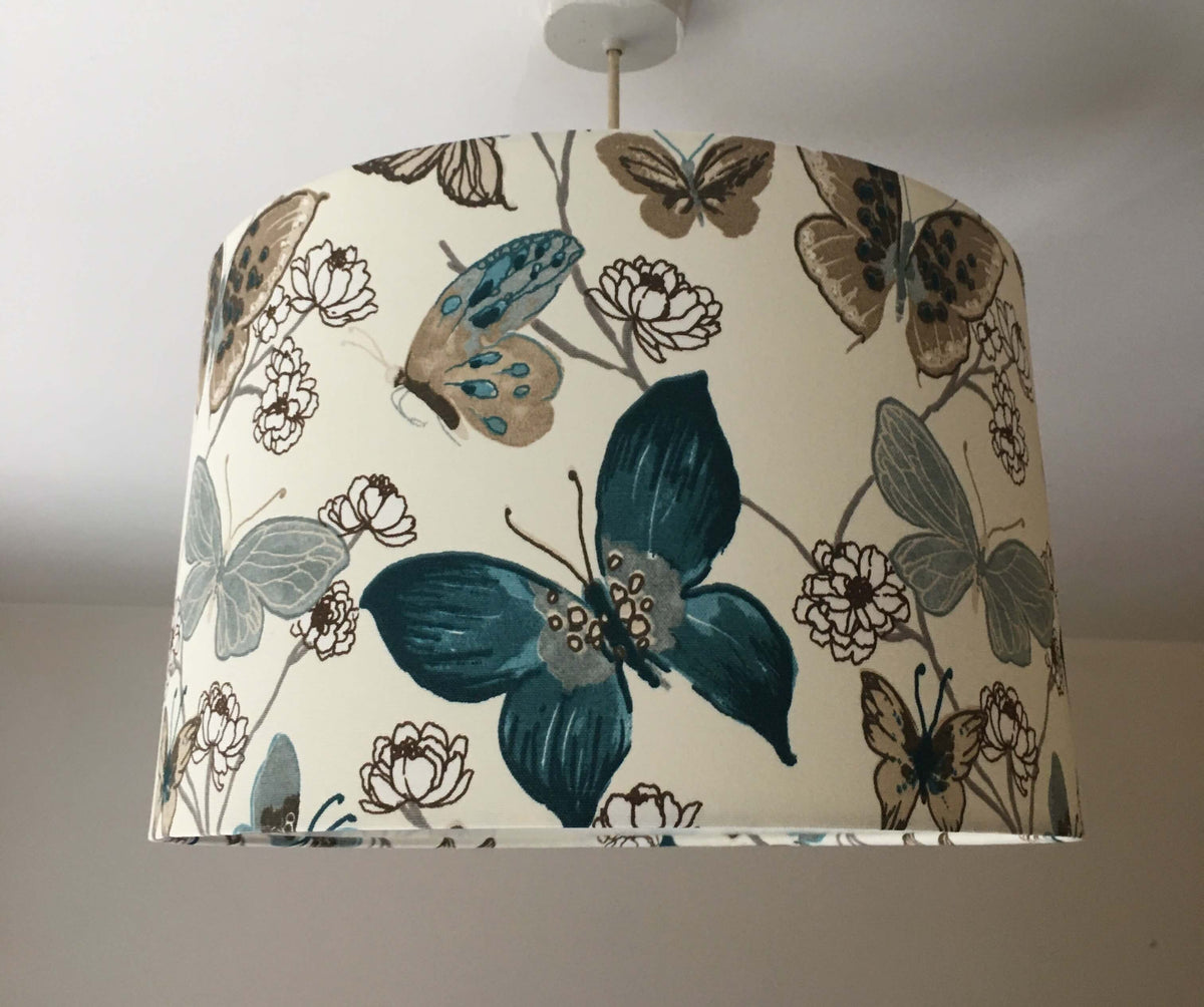 Blue and white lampshade with butterfly and floral pattern on a plain background.