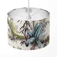 Blue green tropical leaf patterned lampshade on a white background.