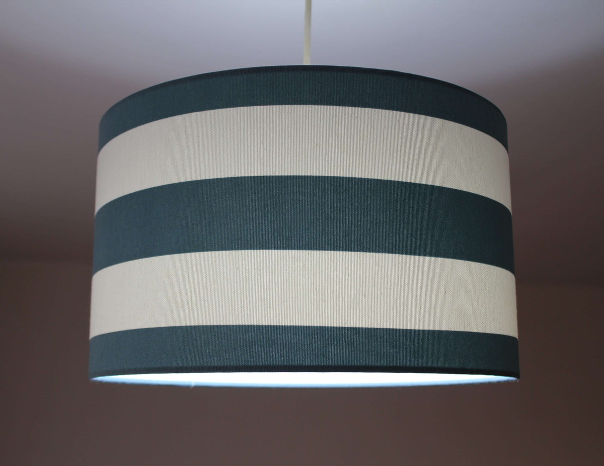 Striped lampshade with dark green and white stripes on a plain background.