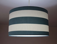 Striped lampshade with dark green and white stripes on a plain background.