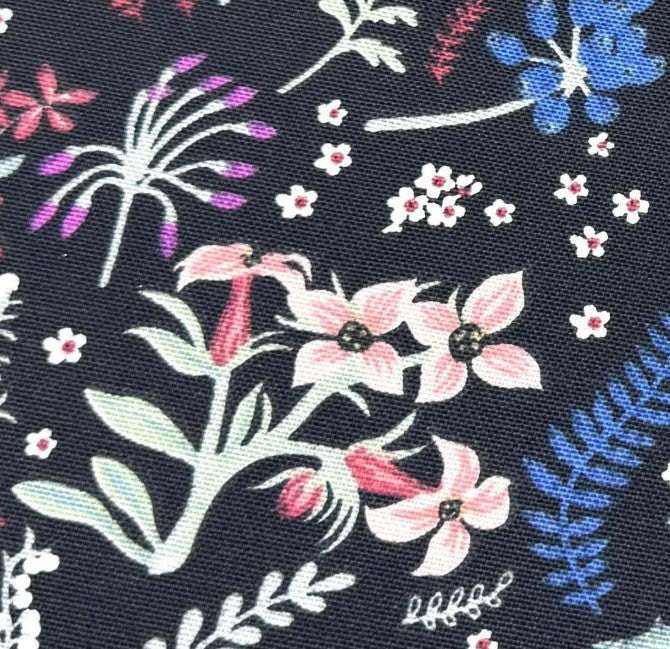 Close-up of pink floral meadow upholstery fabric on dark background.