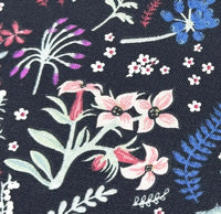 Close-up of pink floral meadow upholstery fabric on dark background.