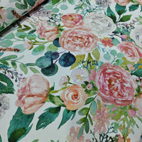 Floral pattern fabric with blush pink flowers and and green leaves on a white background.