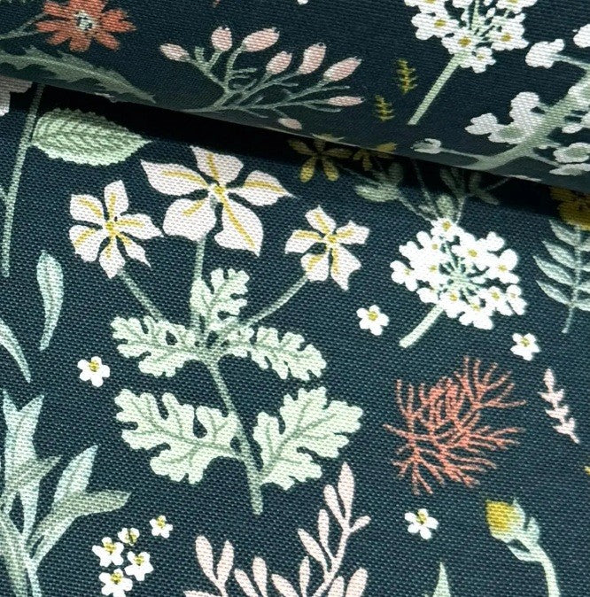 Upholstery fabric printed with white, yellow and coral red flowers on a dark green background.