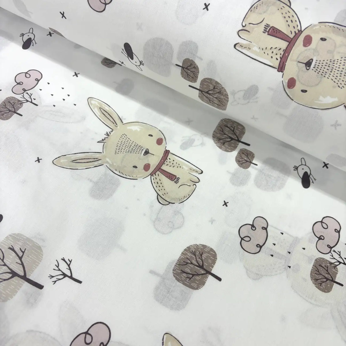 Cotton poplin fabric patterned with woodland rabbits, trees, clouds and birds on a white background