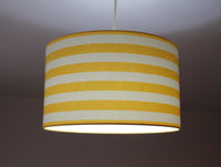Striped lampshade with lemon yellow and white thin stripes on a plain background.