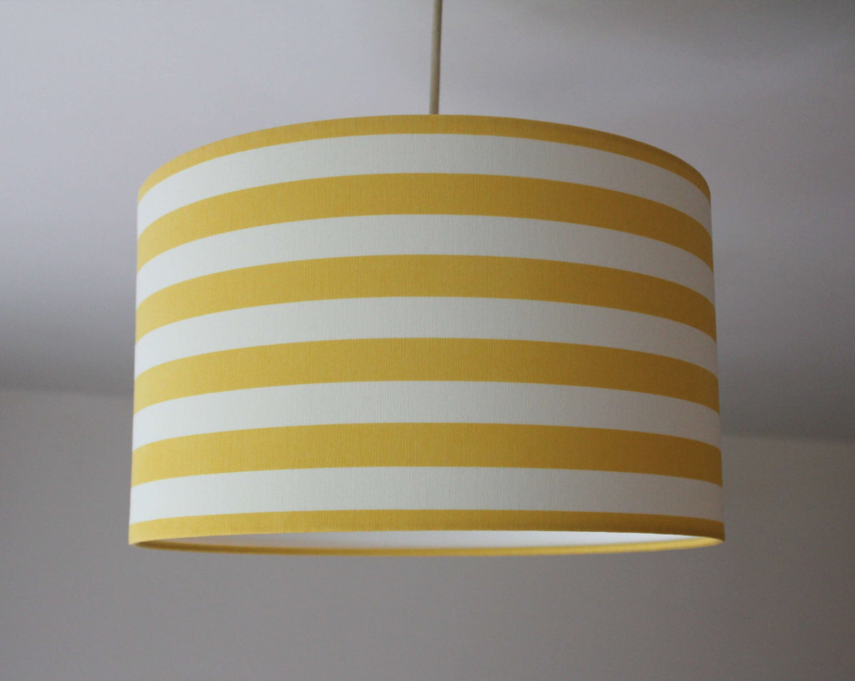Striped lampshade with yellow and white stripes on a plain background.