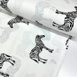 Black and white zebra print cotton fabric featuring safari zebras on a white background.