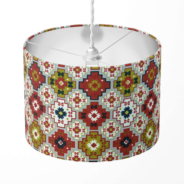 A red, green and grey geometric tile patterned lamp shade on a white background.