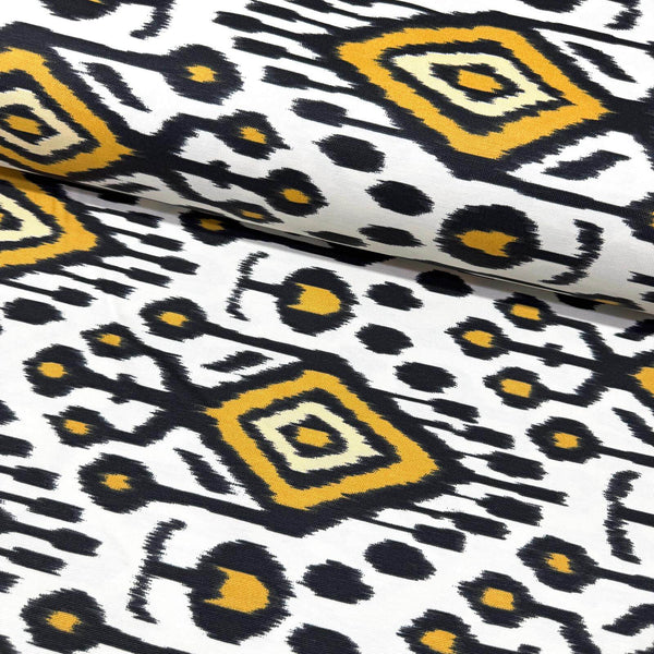 Tribal ikat upholstery fabric with black, yellow, and white geometric pattern.