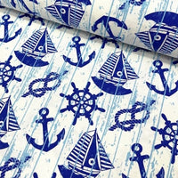 Nautical maritime upholstery fabric patterned with night blue sailboars, wheels, ropes and anchros on a white background.