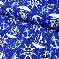 White sailboats, anchors, rope knots and ship wheels printed on royal blue cotton canvas curtain upholstery fabric.
