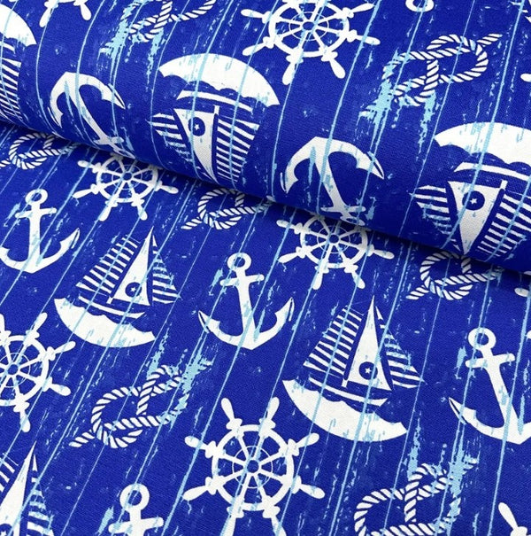 White sailboats, anchors, rope knots and ship wheels printed on royal blue cotton canvas curtain upholstery fabric.