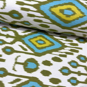 Ikat upholstery curtain fabric with green and blue geometric pattern on a white background.