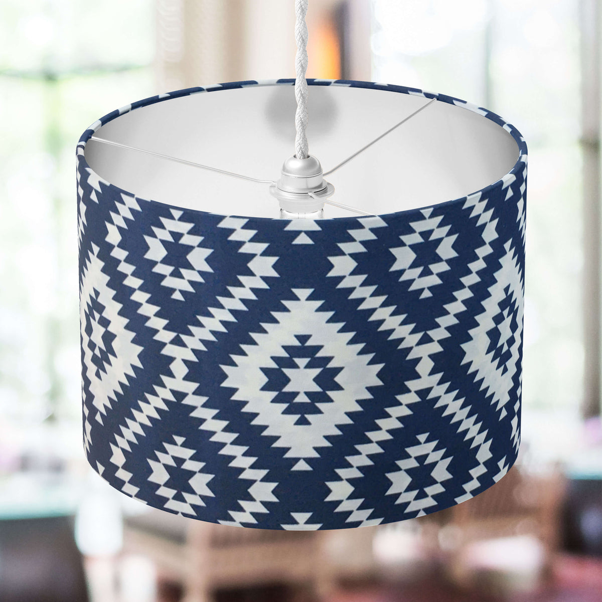 Navy blue and white ethnic patterned lampshade hanging in a room with blurred background.