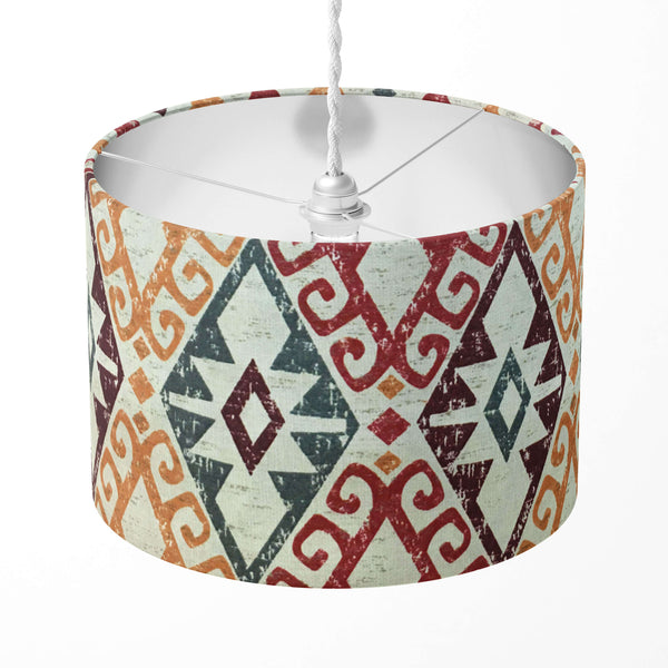 A drum kilim lampshade with a geometric diamond pattern in red and orange colors, designed for use with table lamps, ceiling pendants, or floor lamps.