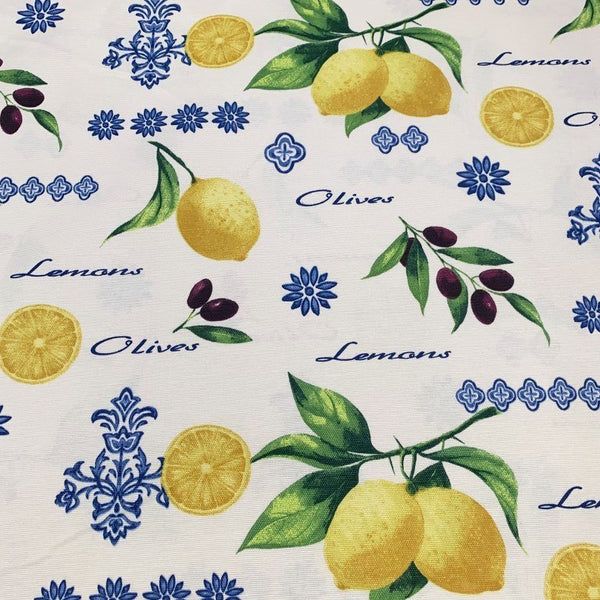 Yellow lemons and black olives with green leaves and blue decorations printed on white cotton canvas upholstery fabric.