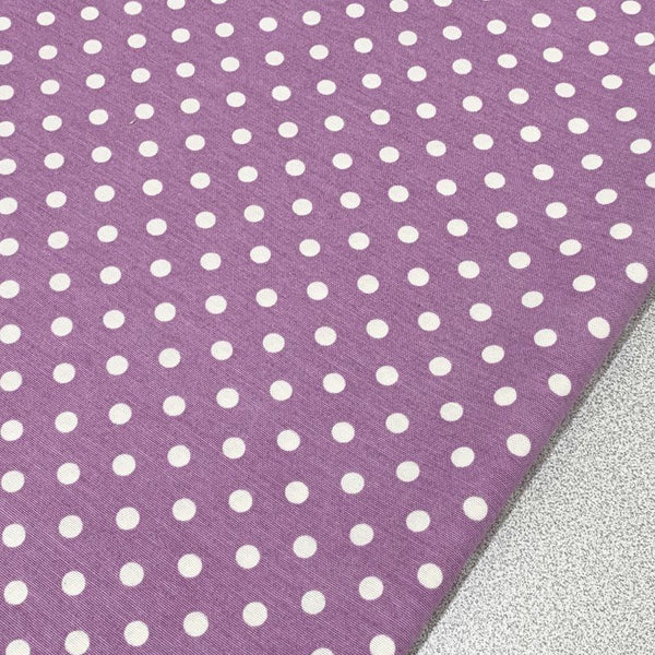 Polka dot upholstery fabric printed with white spots on lilac.