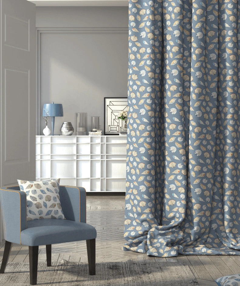 Living room with a nautical patterned blue and white curtain, cushion and chair.