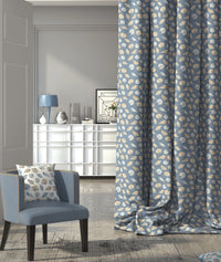 Living room with a nautical patterned blue and white curtain, cushion and chair.