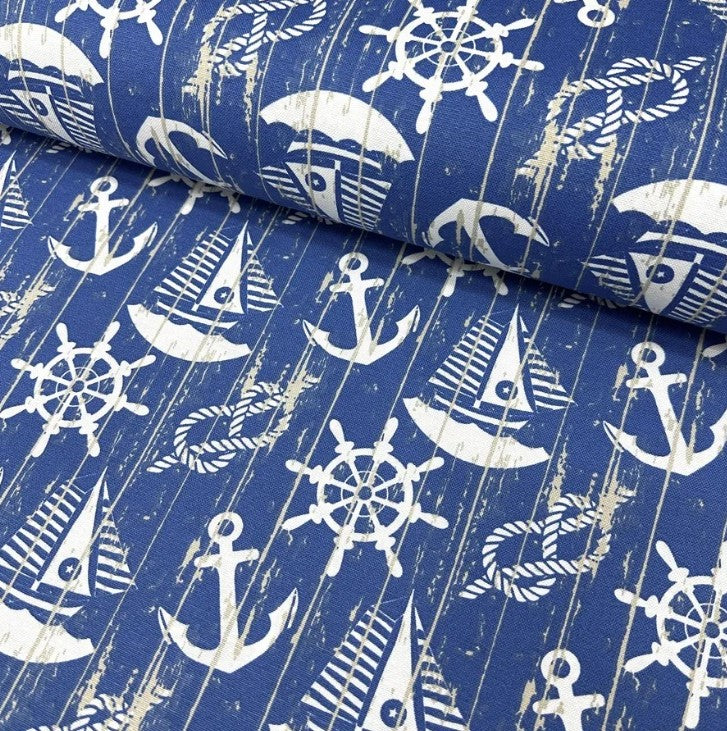 Cotton canvas fabric printed with white sailboats, anchors, knot ropes, ship wheels and denim blue sea.