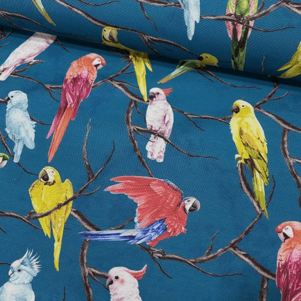 Tropical bird upholstery fabric patterned with red, yellow, light pink and light blue parrots on a deep blue background. 