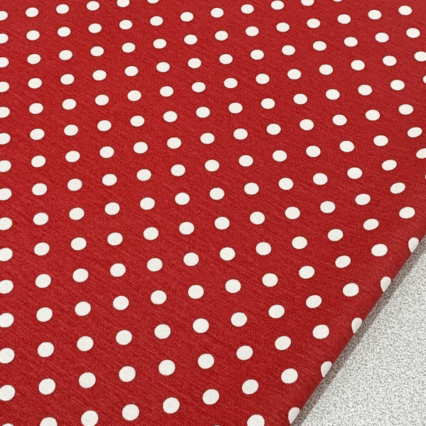 Printed polka dot upholstery fabric with white spots and red background.