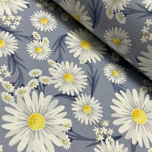 Upholstery curtain fabric patterned with yellow and white daisy flowers on denim blue background.