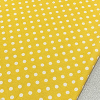 Yellow polka dot cotton canvas upholstery fabric with white spots on it.