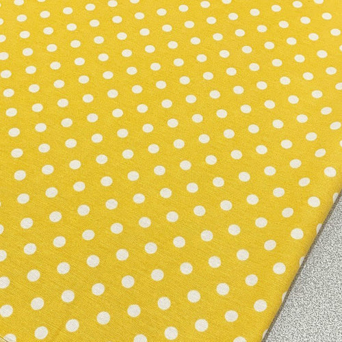 Yellow polka dot cotton canvas upholstery fabric with white spots on it.