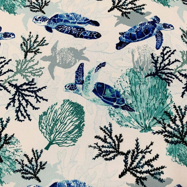 A fabric featuring a pattern with sea turtles and marine life against a blue ocean reef background, suitable for nautical-themed upholstery or home decor projects.